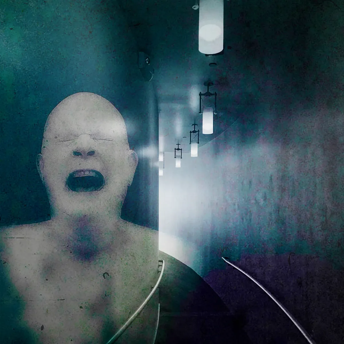 A dimly lit corridor that curves towards nowhere. A ghostly anguished face is superimposed on the wall.