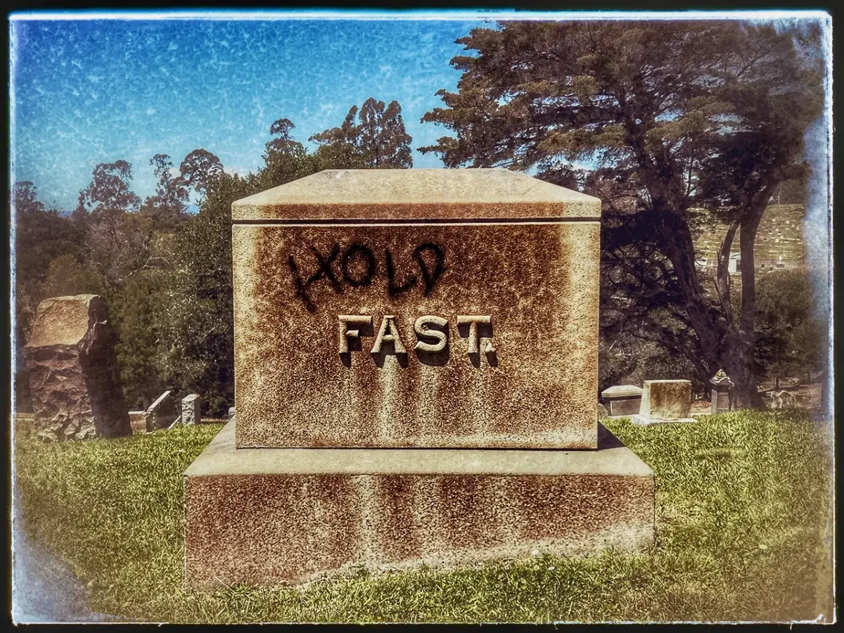 Vintage photo of a gravestone with the name, "Fast."  Someone has spray-painted the word "Hold" above it.